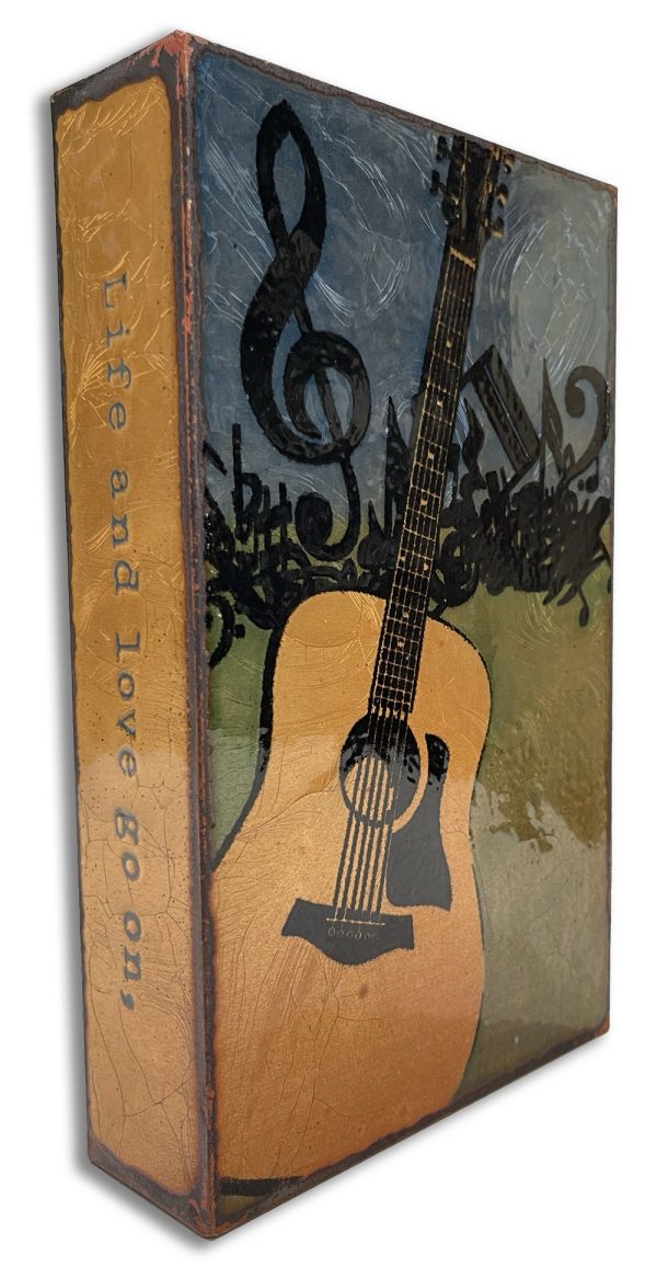 Retired Spiritile #30 - In Tune “Life and love go on. Let the music play.” – Johnny Cash Enamel and copper bricks with a colorful image and inspiring quote. This one features a quote by Johnny Cash and an acoustic guitar with music notes jumbled above