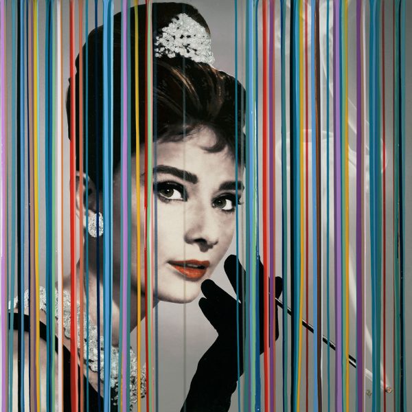 Hand embellished limited edition print on canvas of a young Audrey Hepburn set behind a curtain of colorful lines.