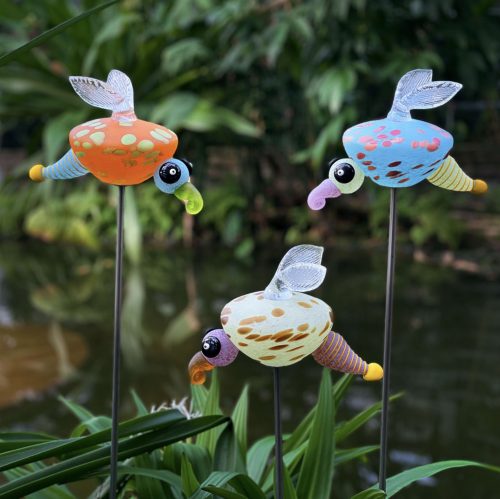 Whimsical firefly glass sculpture on aluminum stick. Shown in three colors: light green, light blue, and orange. outdoor sculpture