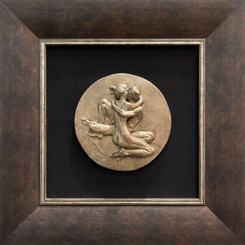 Bronze colored sculpture of a man and woman nude embracing. Framed with a black background and rustic bronze frame.
